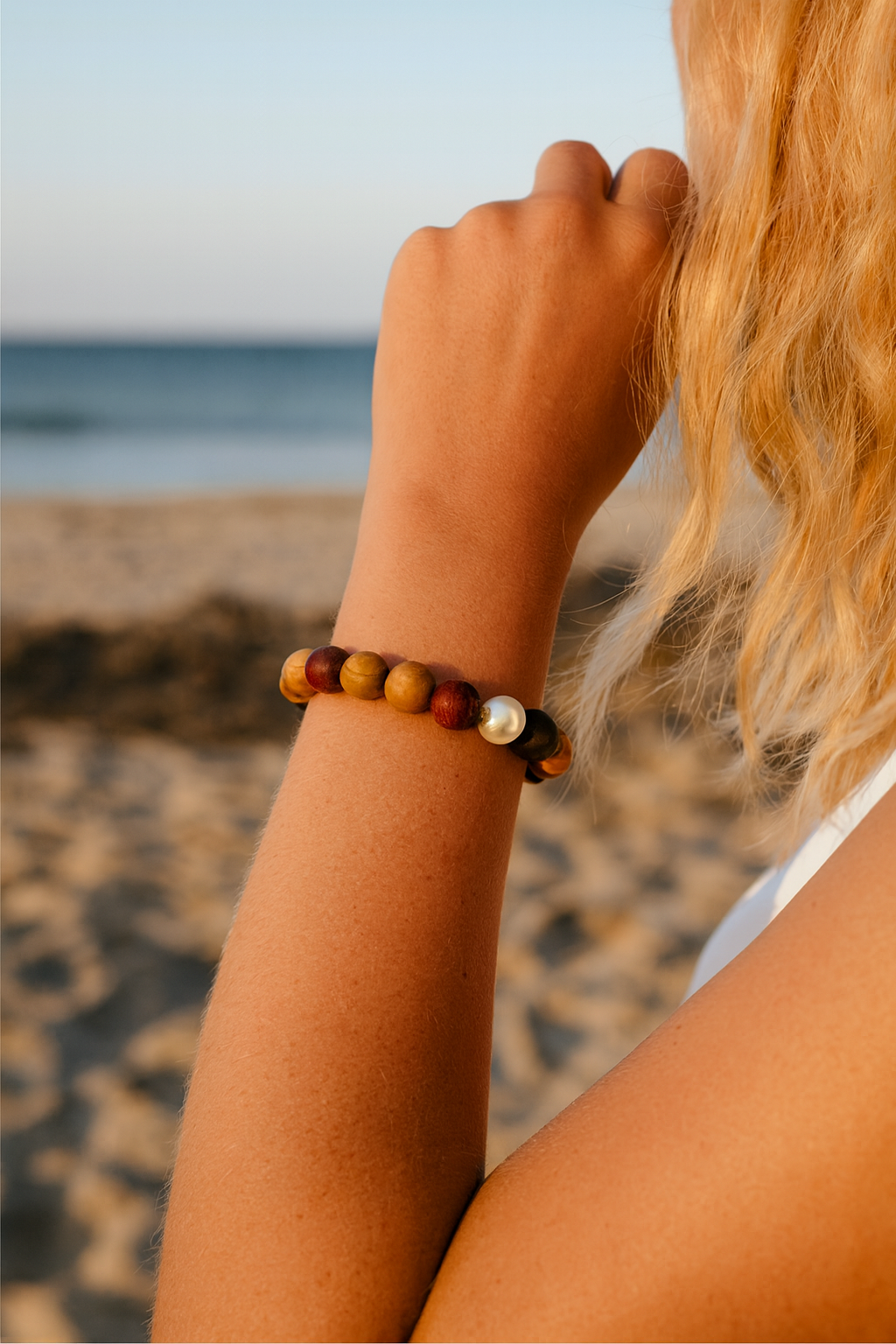 Female wearing an Arafura bracelet with a South Sea pearl in the middle and mixed wood beads.